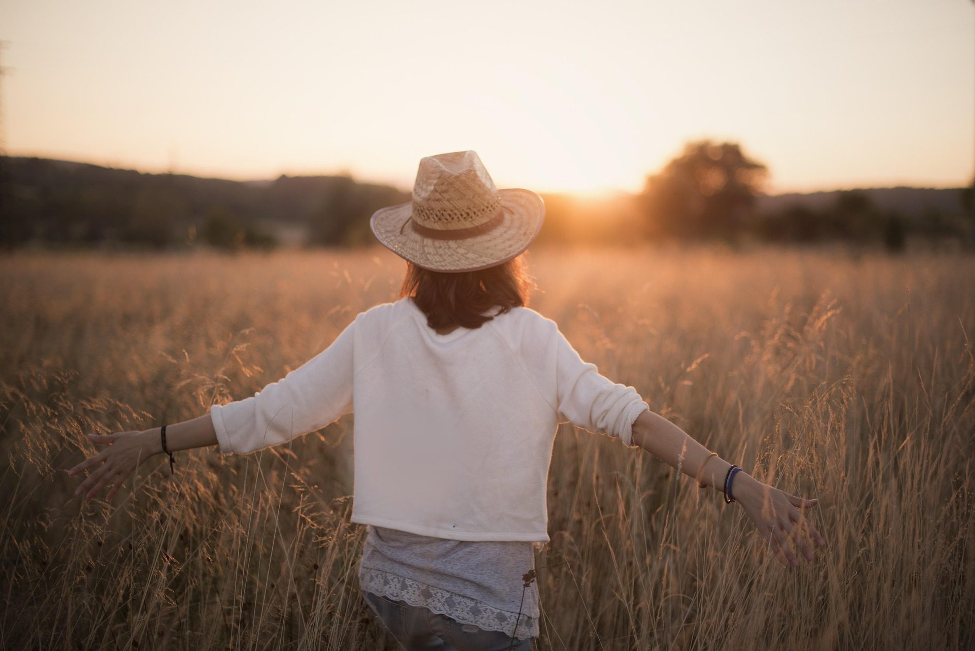 Femme sereine dans un champ au coucher du soleil, apaisée après sa consultation de voyance par téléphone